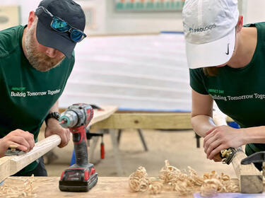 Zwei Mitarbeiter von Prologis schleifen Holz bei einem Projekt am IMPACT Day